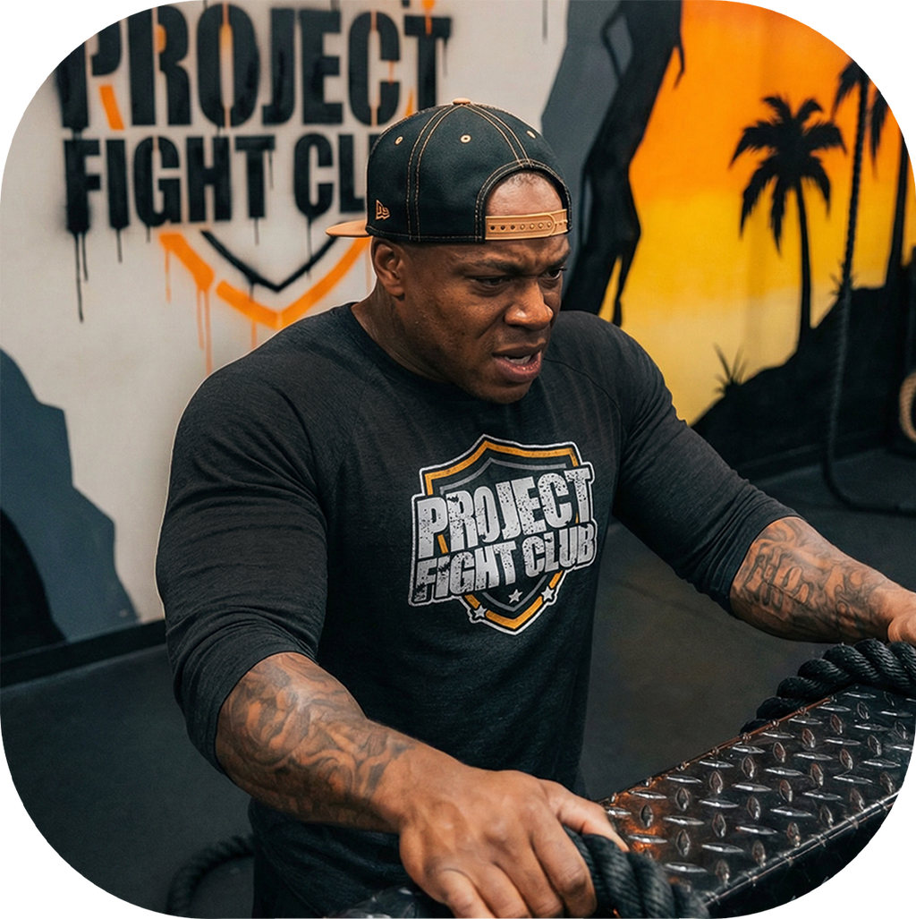 Man wearing a 'Project Fight Club' t-shirt in front of a branded wall.